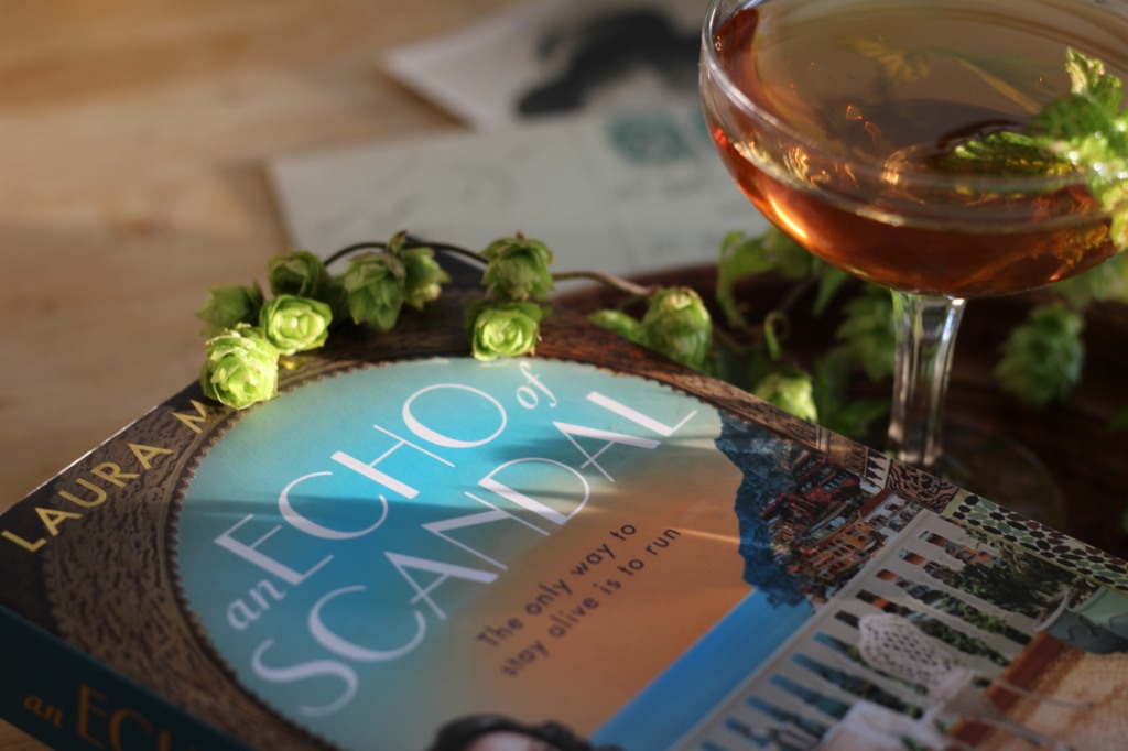 Close up of cover of An Echo of Scandal and cocktail